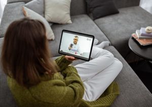 woman on couch talking with doctor as part of virtual healthcare solutions