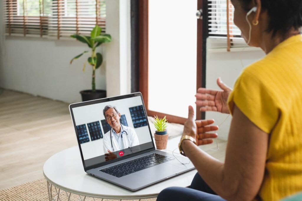 woman in yellow shirt talking on laptop with doctor about paying for second opinions