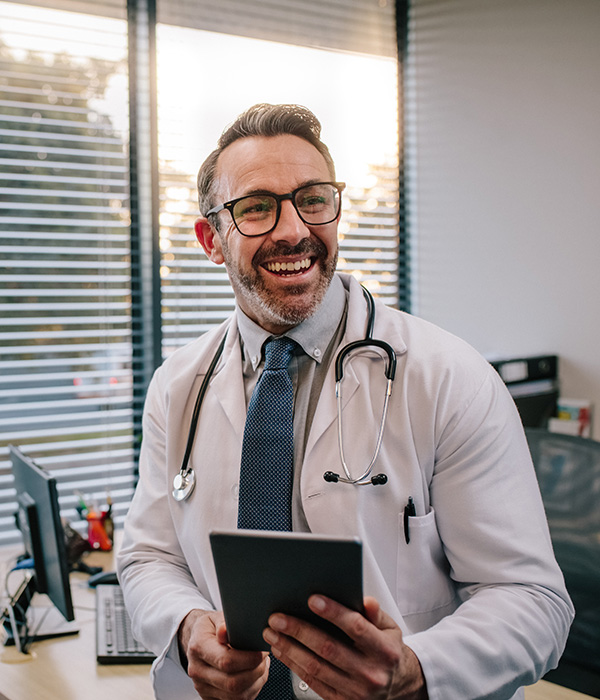 a man in a white coat and glasses holding a tablet